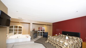 Une chambre avec un grand lit, une télévision, une baignoire et une cheminée.
