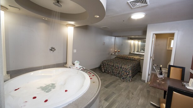 Une salle de bain moderne avec une grande baignoire, une douche et un lit recouvert d’une couvre-lit à motifs floraux.