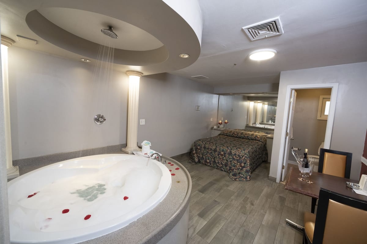 Un baño moderno con una bañera grande, una ducha y una cama con colcha estampada de flores.