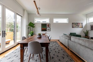 Una sala moderna con una mesa de comedor de madera, sofás grises y una alfombra estampada.