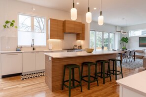 Una cocina moderna con una isla grande, armarios de madera y taburetes de bar verdes.