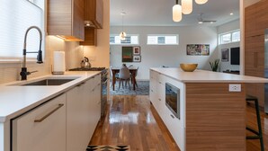 A modern kitchen with wooden cabinets, a large island, and pendant lighting. - Modernist Masterpiece: 'Simply the Best' (Durham)