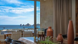 A dining area with a view of the ocean and rocky formations. - Stunning New Luxury Condo with Breathtaking Ocean Views (El tezal)