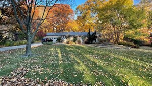 A residential area with a house, a driveway, and a lawn with fallen leaves. - Boiler Bungalow - entire 3(King)Bed home! (West Lafayette)