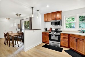 A modern kitchen with wooden cabinets, stainless steel appliances, and a dining area with a table and chairs.