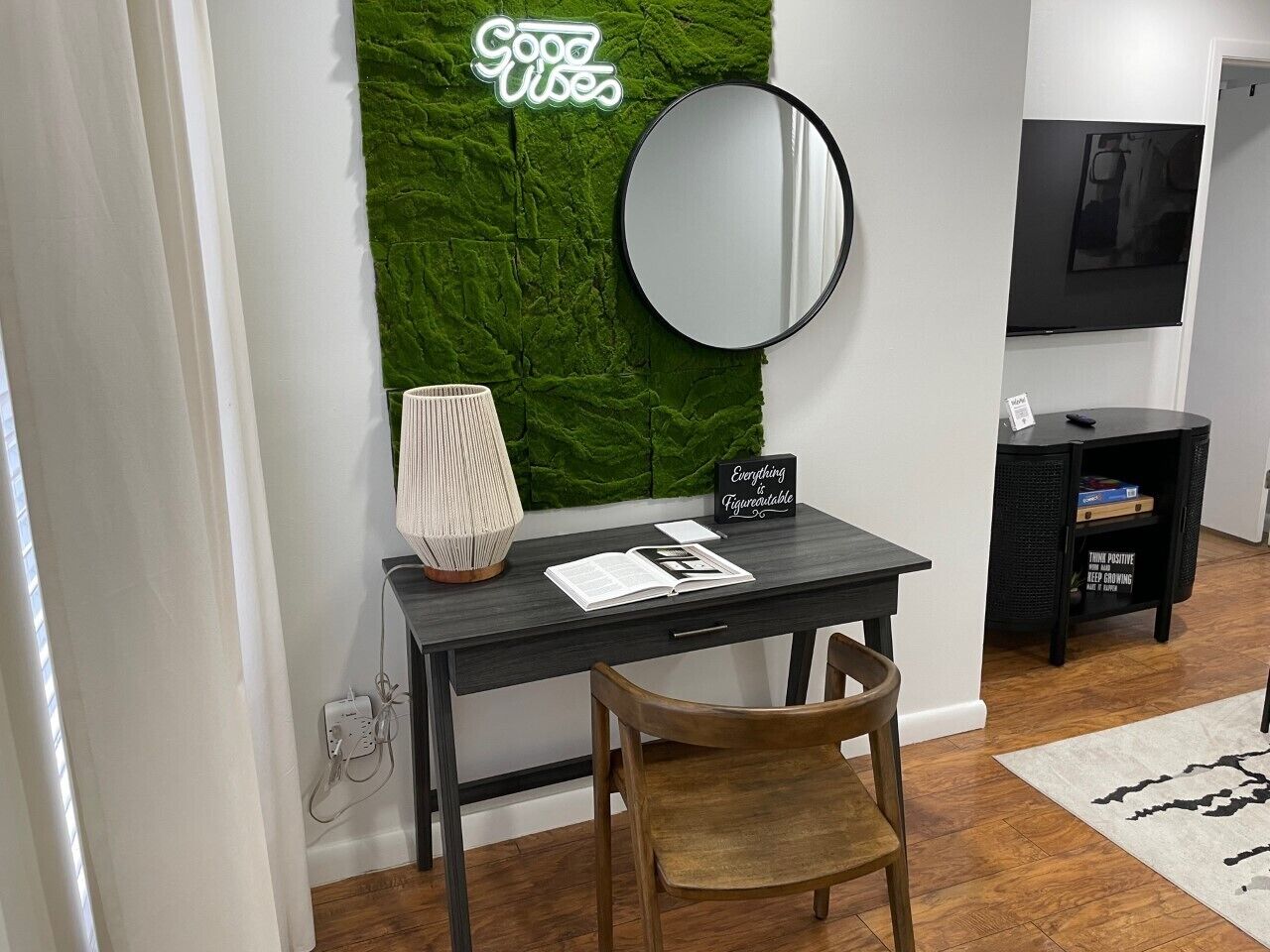 Un espacio de oficina moderno con escritorio, silla, pared verde, espejo y un cartel motivacional.