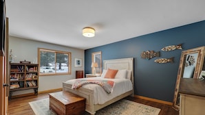 A bedroom with a bed, wooden dresser, bookshelf, and decorative fish wall art. - Chain of Lakes Waterfront Home (Central Lake)