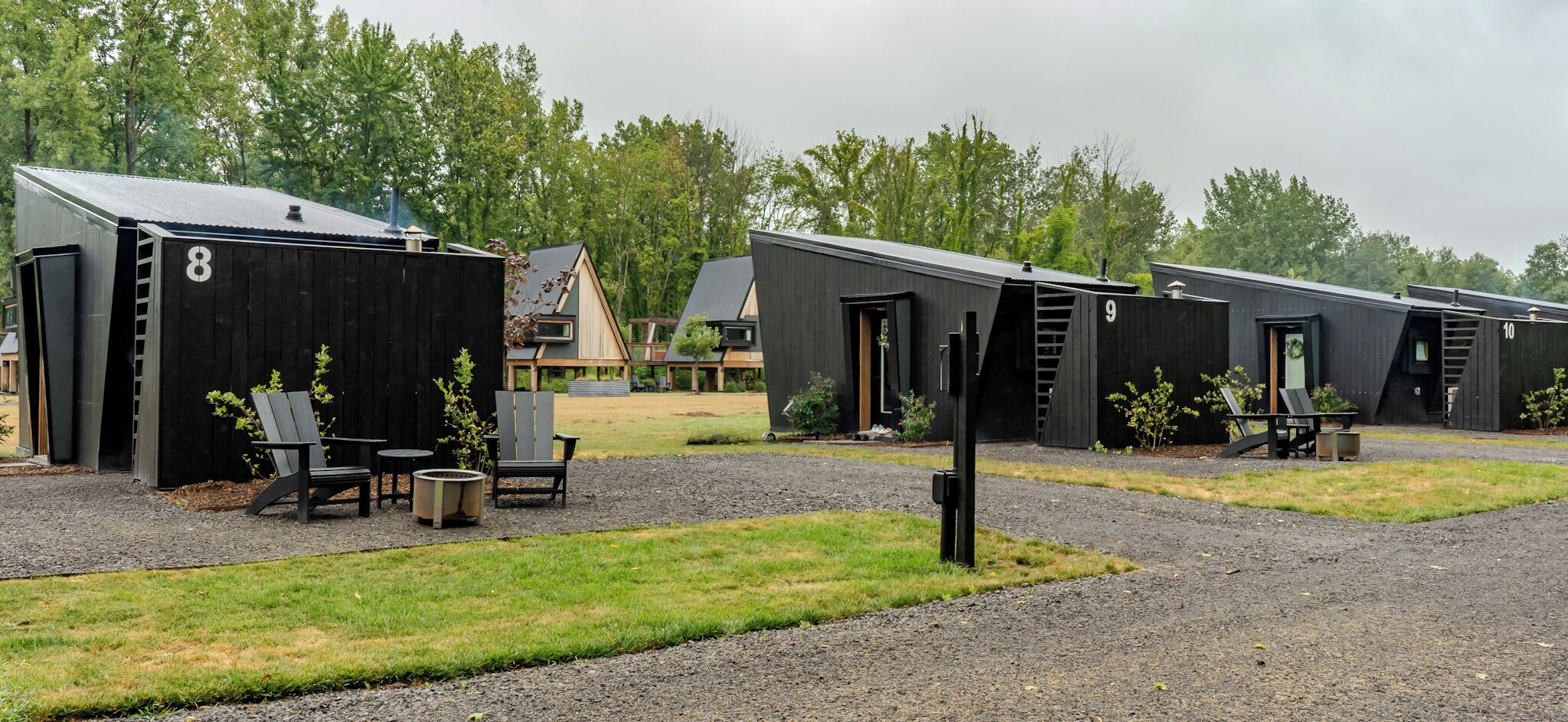 A row of numbered cabins with outdoor seating and a gravel path.
