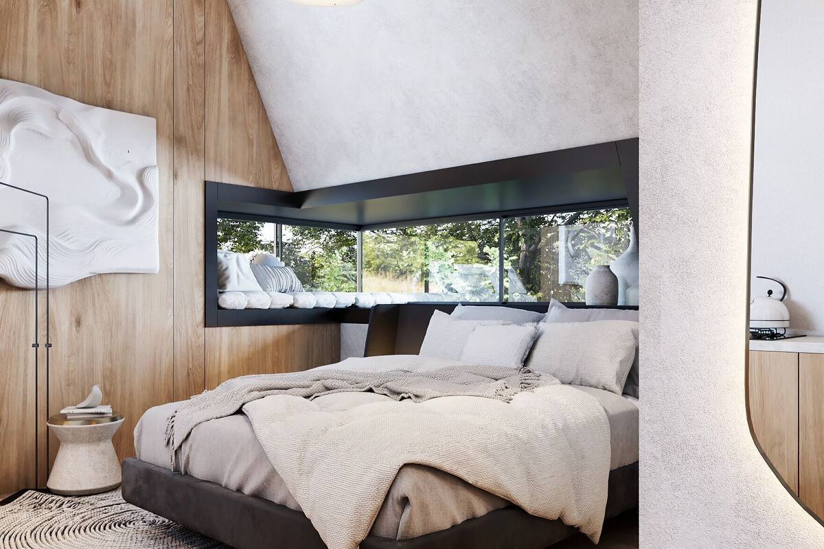 A modern bedroom with a bed, a round mirror, and a view of the outdoors.