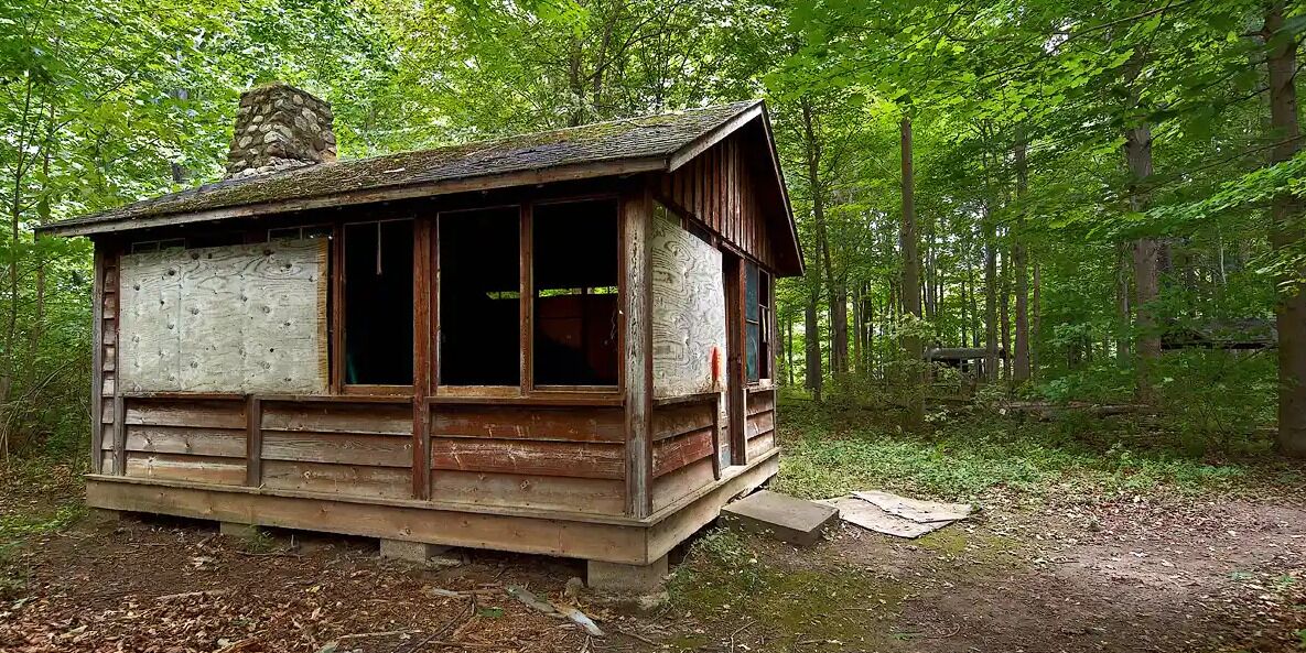 A rustic cabin with a wooden exterior, large windows, and a chimney.
