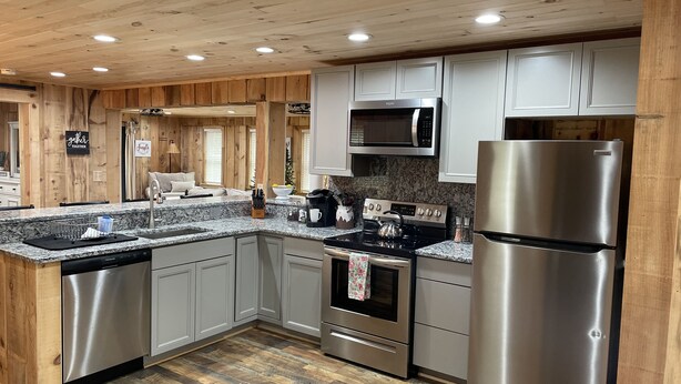 A modern kitchen with wooden accents, stainless steel appliances, and a granite countertop. - Ridgeview Cottage (Lexington)