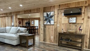 A wooden-paneled room with a sofa, a small table, a decorative wall piece, and a wooden cabinet with a chess set. - Ridgeview Cottage (Lexington)