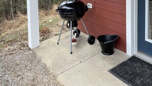 A barbecue grill outside a house with a red exterior and a white porch. - Ridgeview Cottage (Lexington)