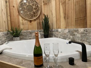 Un baño con una bañera grande, una botella de champán y dos copas.