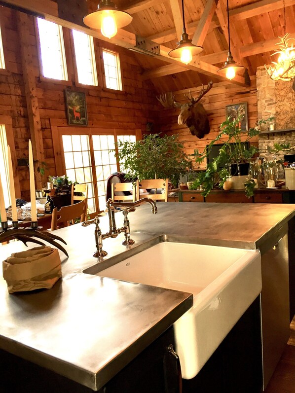 Una cocina rústica con una isla grande, vigas de madera y una decoración de cabeza de ciervo.