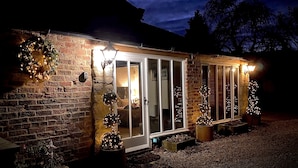 A brick building with a glass door entrance, decorated with Christmas lights and small trees. - Grange Farm Lodge (Ripon)