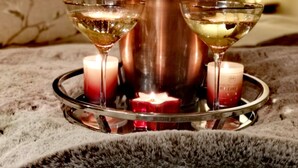 A tray with two martini glasses, a bottle, and two candles on a textured surface. - Grange Farm Lodge (Ripon)
