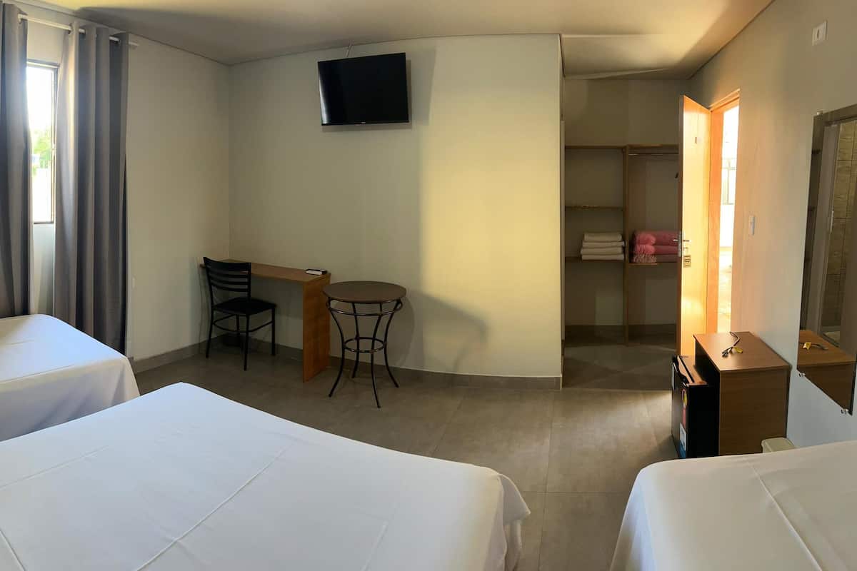 Een hotelkamer met twee bedden, een bureau, een stoel, een televisie en een kledingkast.