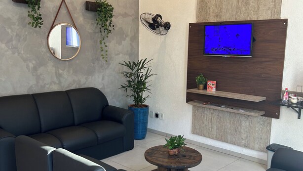 Una sala de estar moderna con un sofá negro, una mesa de centro redonda y un televisor montado en un panel de madera.