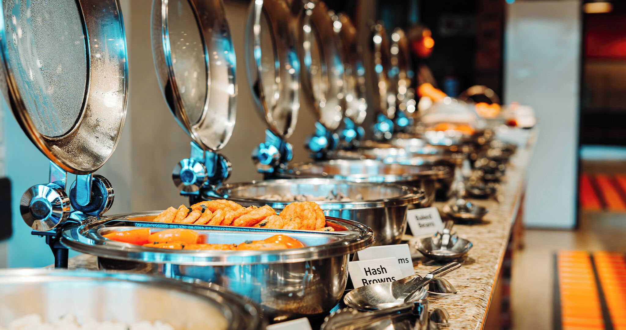 A buffet line with various food items and utensils.