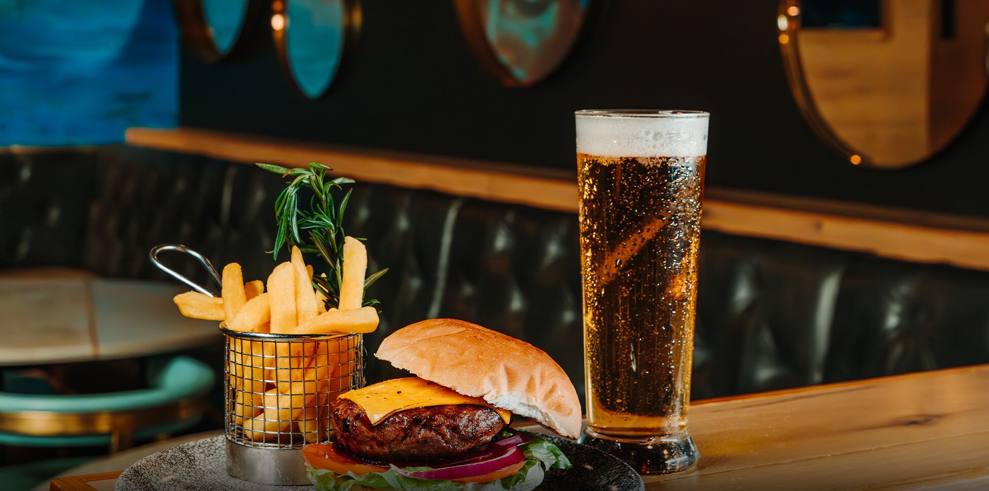 Un hamburger, des frites et un grand verre de bière sur une table dans un restaurant.