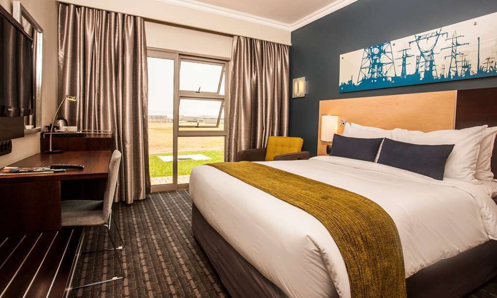 Une chambre d’hôtel avec un lit, un bureau, une chaise et une vue sur l’extérieur.