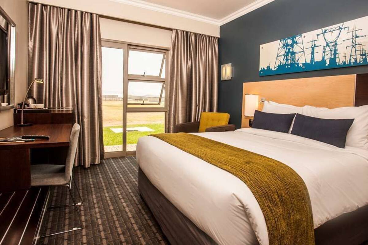 Une chambre d’hôtel avec un lit, un bureau, une chaise et une vue sur l’extérieur.