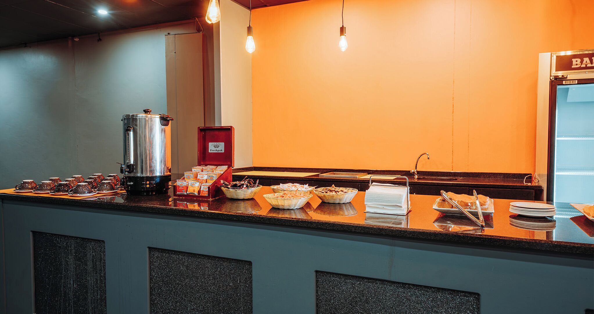Zona de bufé con una máquina de café, diferentes alimentos y un letrero que dice "BA".