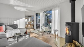 A modern living room with a fireplace, a dining area, and a view of the outdoors. - 4 bedroom cozy home in Odder (Odder)
