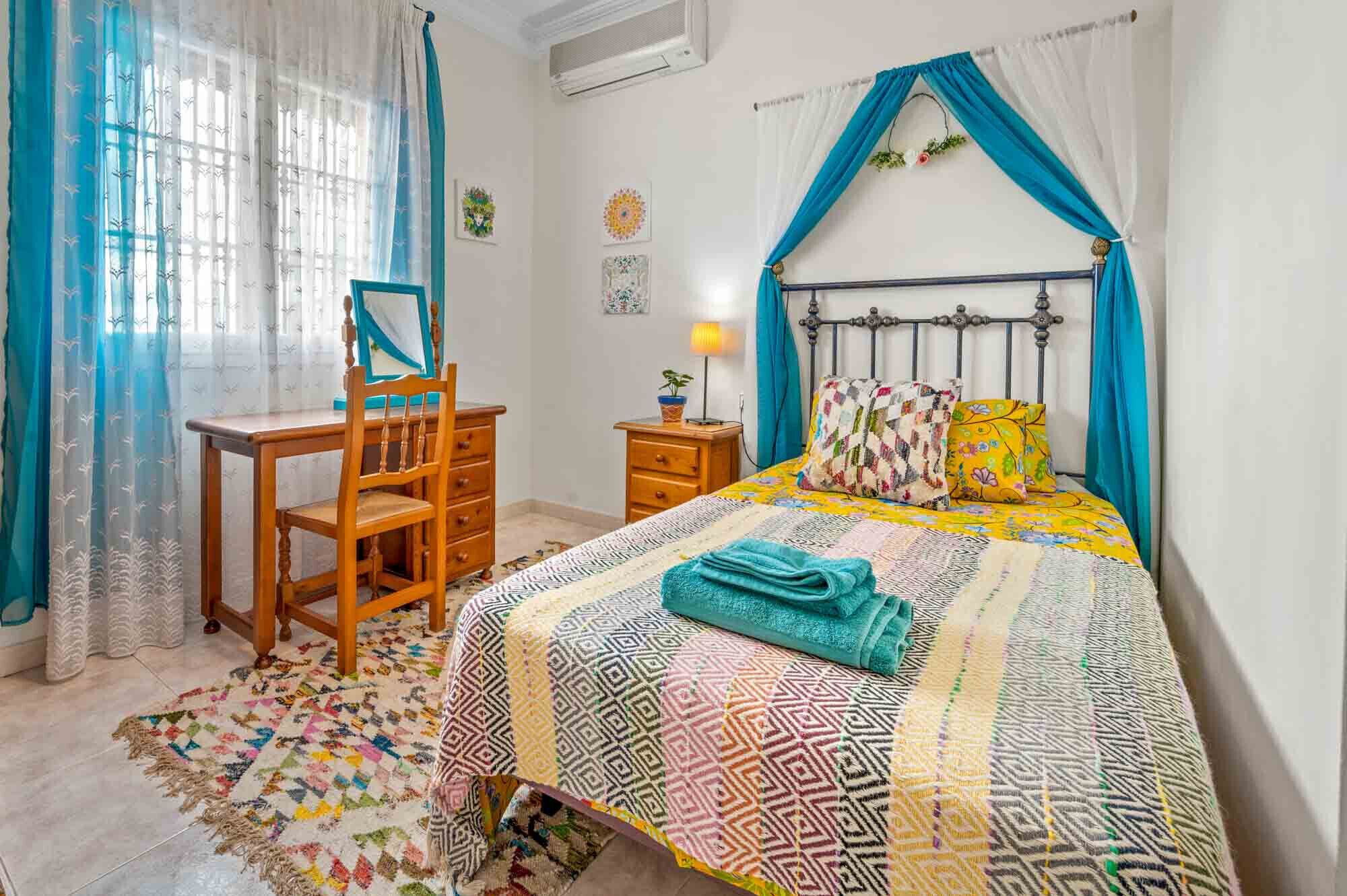 A bedroom with a bed, a desk, and a chair.