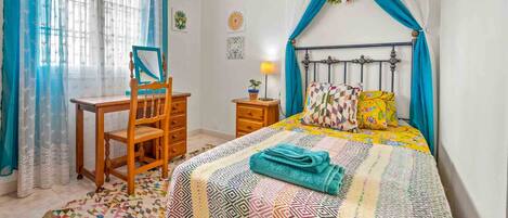 A bedroom with a bed, a desk, and a chair.