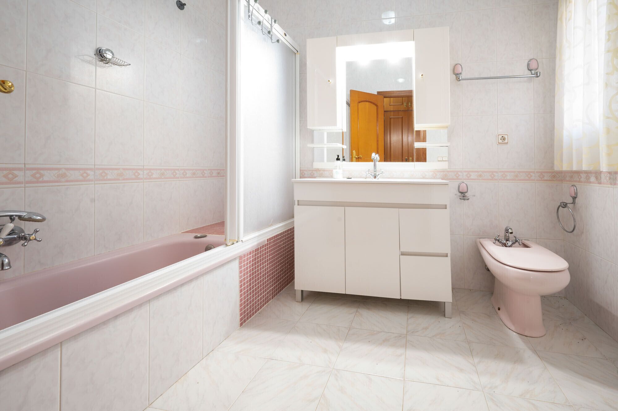 A bathroom with a bathtub, a sink, and a toilet. There is a mirror above the sink and a towel rack on the wall.