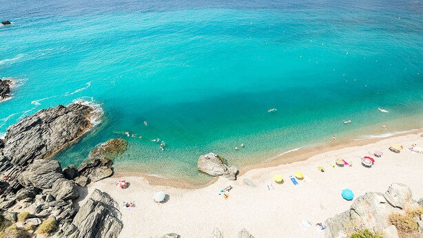 A beach with clear turquoise water, rocky coastline, and a sandy shore with beach umbrellas. - Noria Del Mar (Almuñecar)