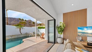 Una sala de estar moderna con piscina, televisor grande y vistas a las montañas.