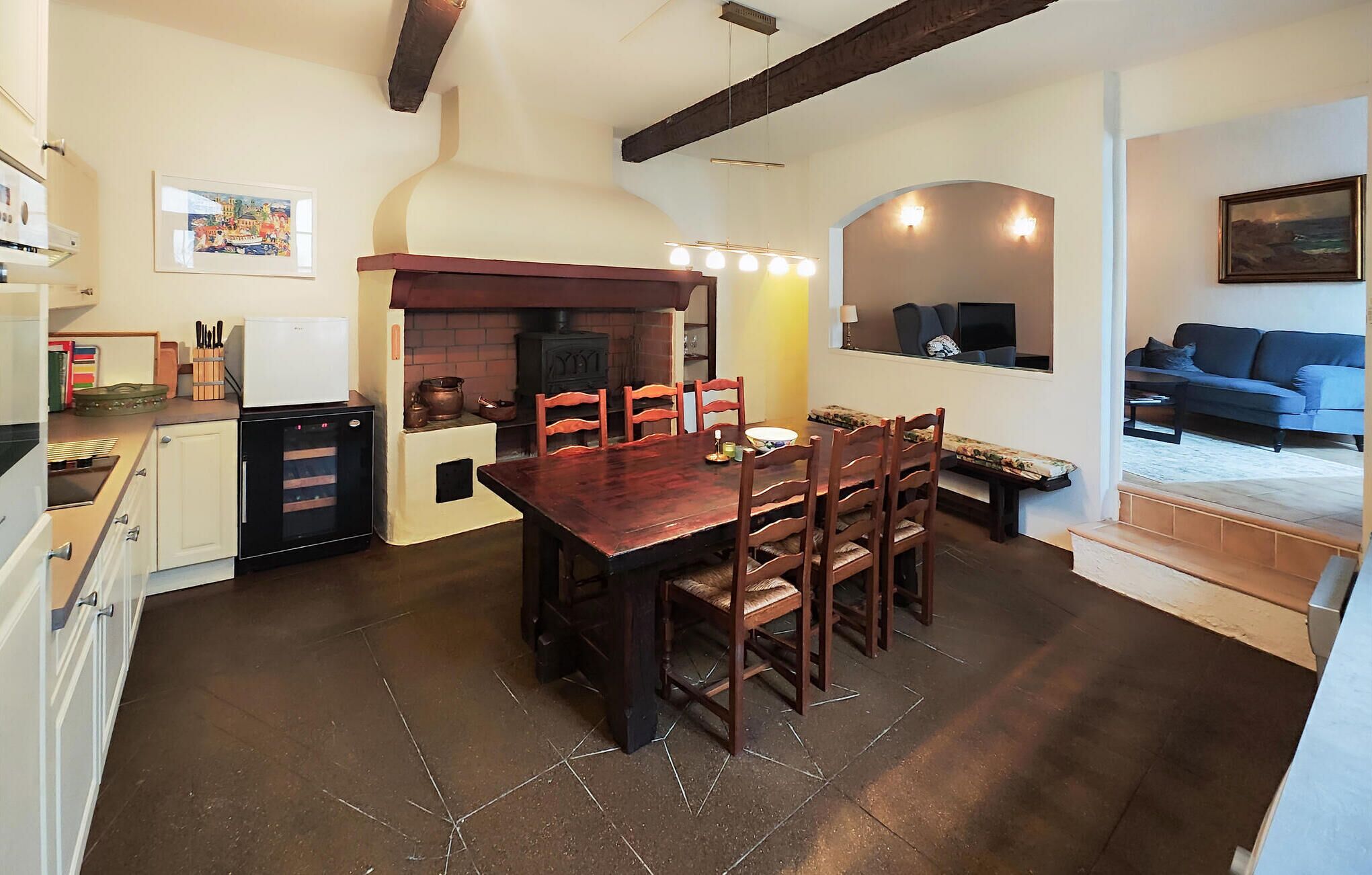 A cozy kitchen with a wooden table and chairs, a built-in oven, and a dining area with a sofa and TV.