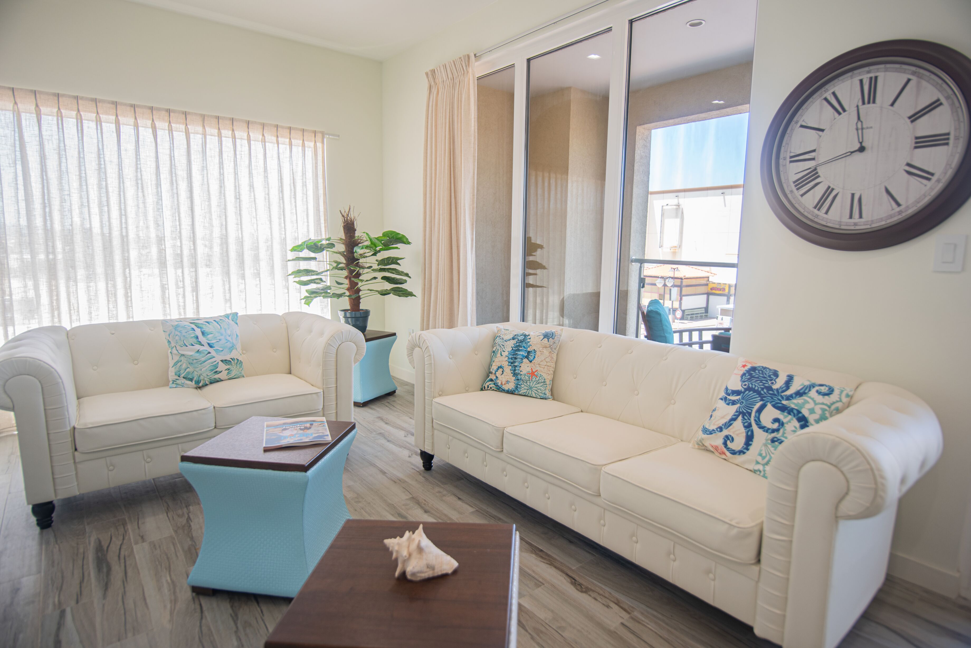 A living room with two white sofas, a coffee table, and a large wall clock.