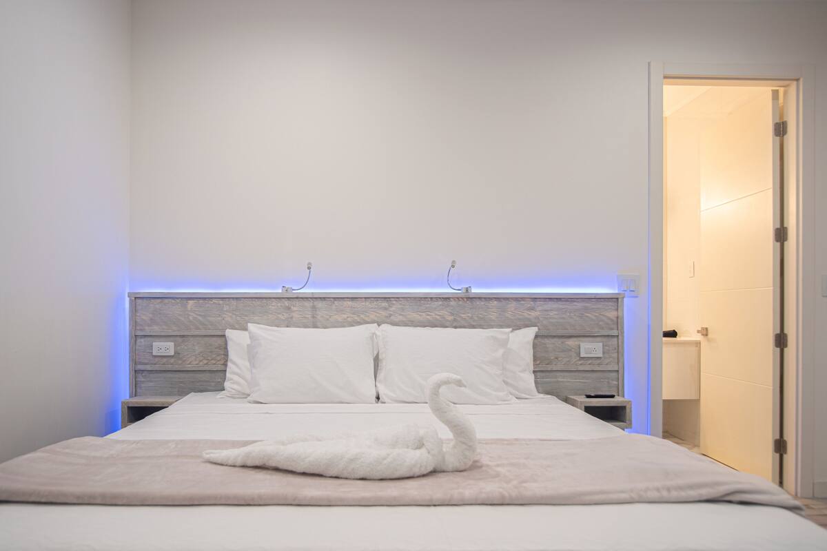 A neatly made bed with a swan-shaped pillow and a swan-shaped towel on the bed.