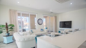 A modern living room with a white sofa, a coffee table, and a large window.