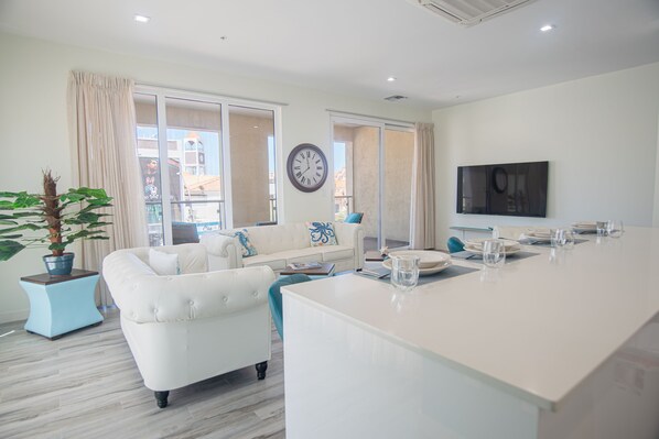 A modern living room with a white sofa, a coffee table, and a large window.