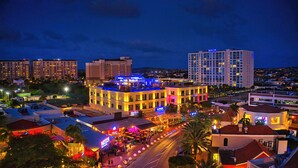 A multi-story hotel with a rooftop bar, surrounded by other buildings and a busy street.