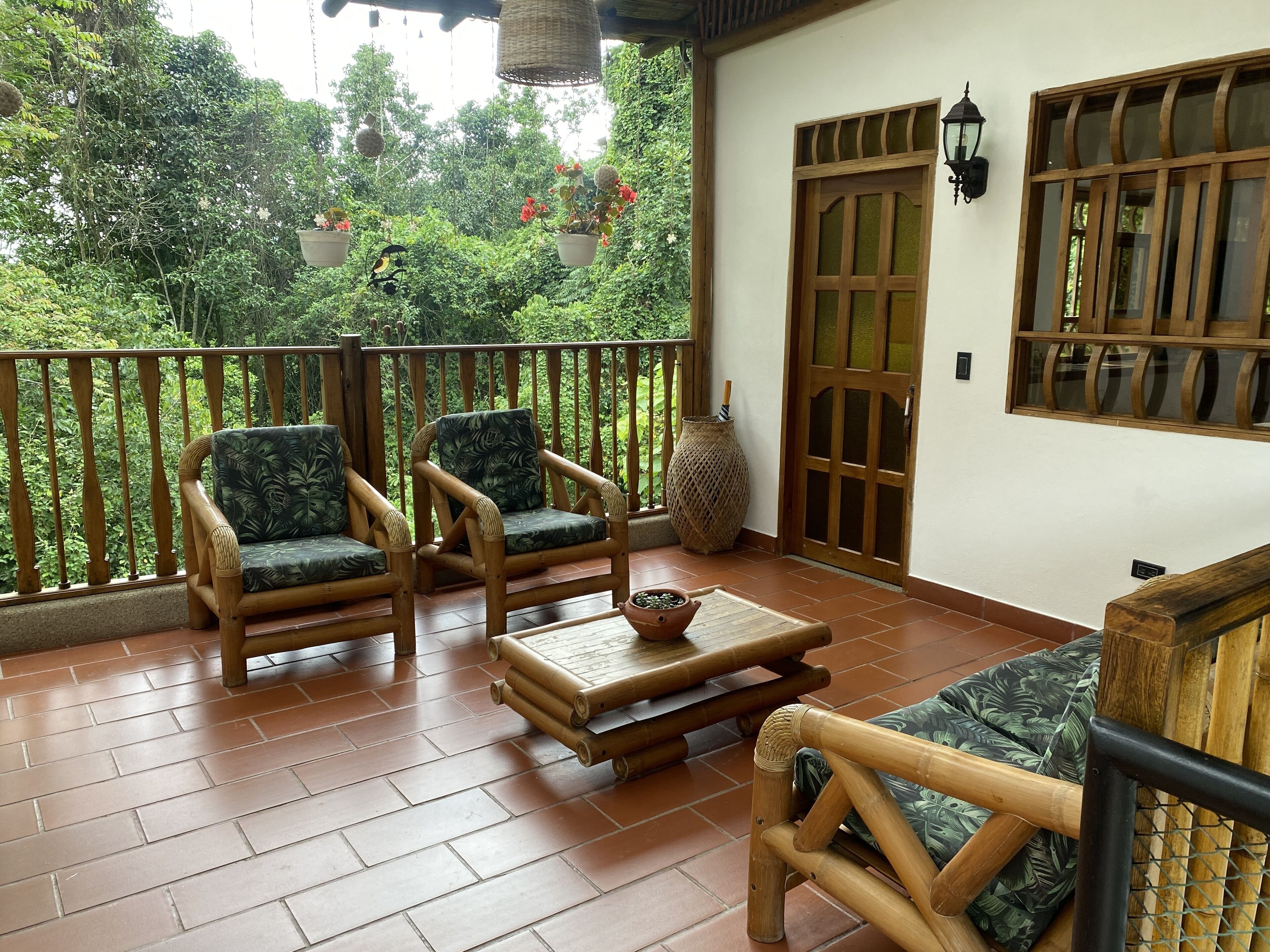 A balcony with two wicker chairs, a small table, and a decorative vase.
