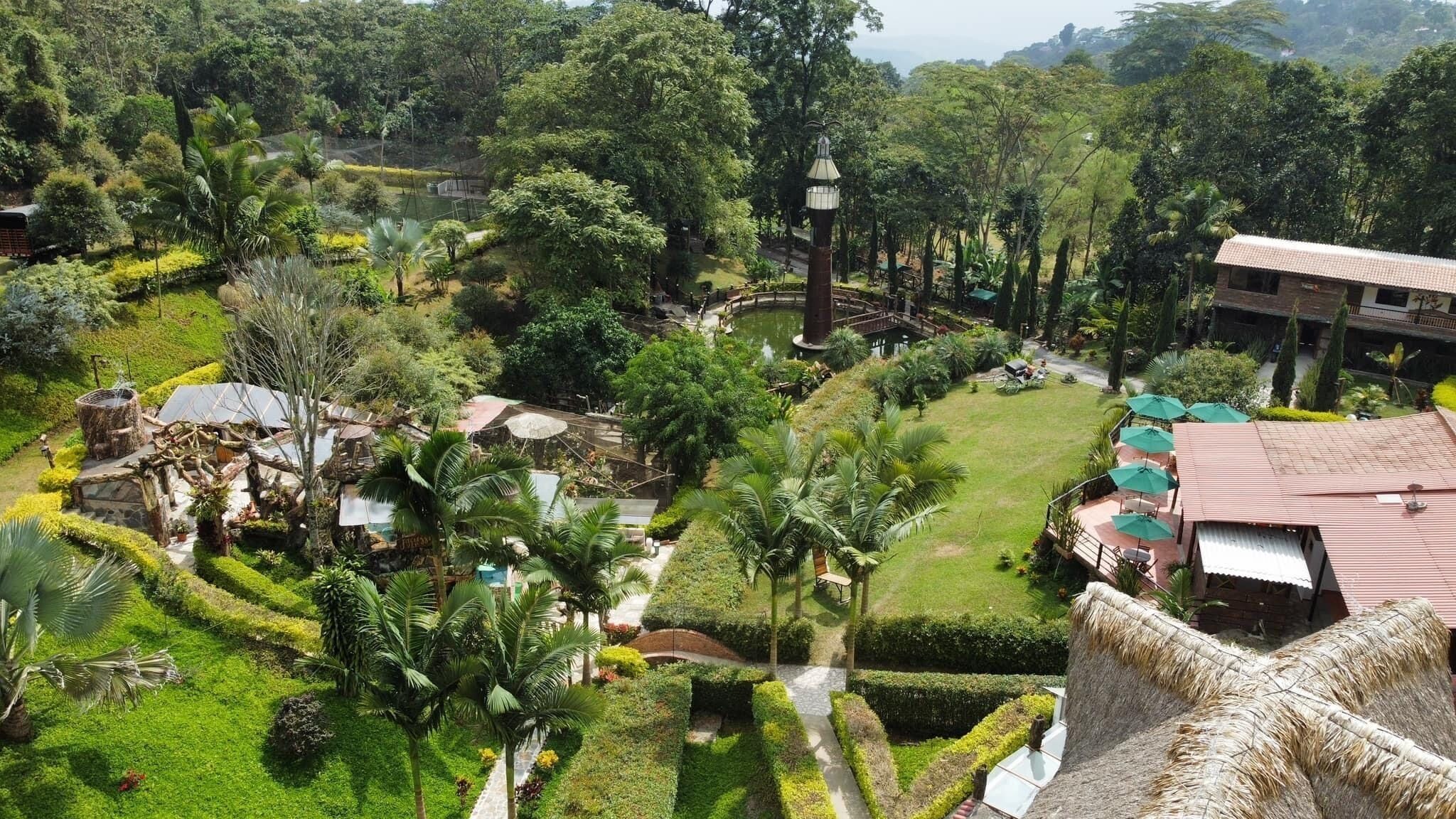A lush garden with a central water feature, a gazebo, and a tower-like structure.