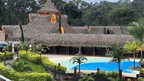 A resort with a thatched-roof building, a swimming pool, and lush greenery.