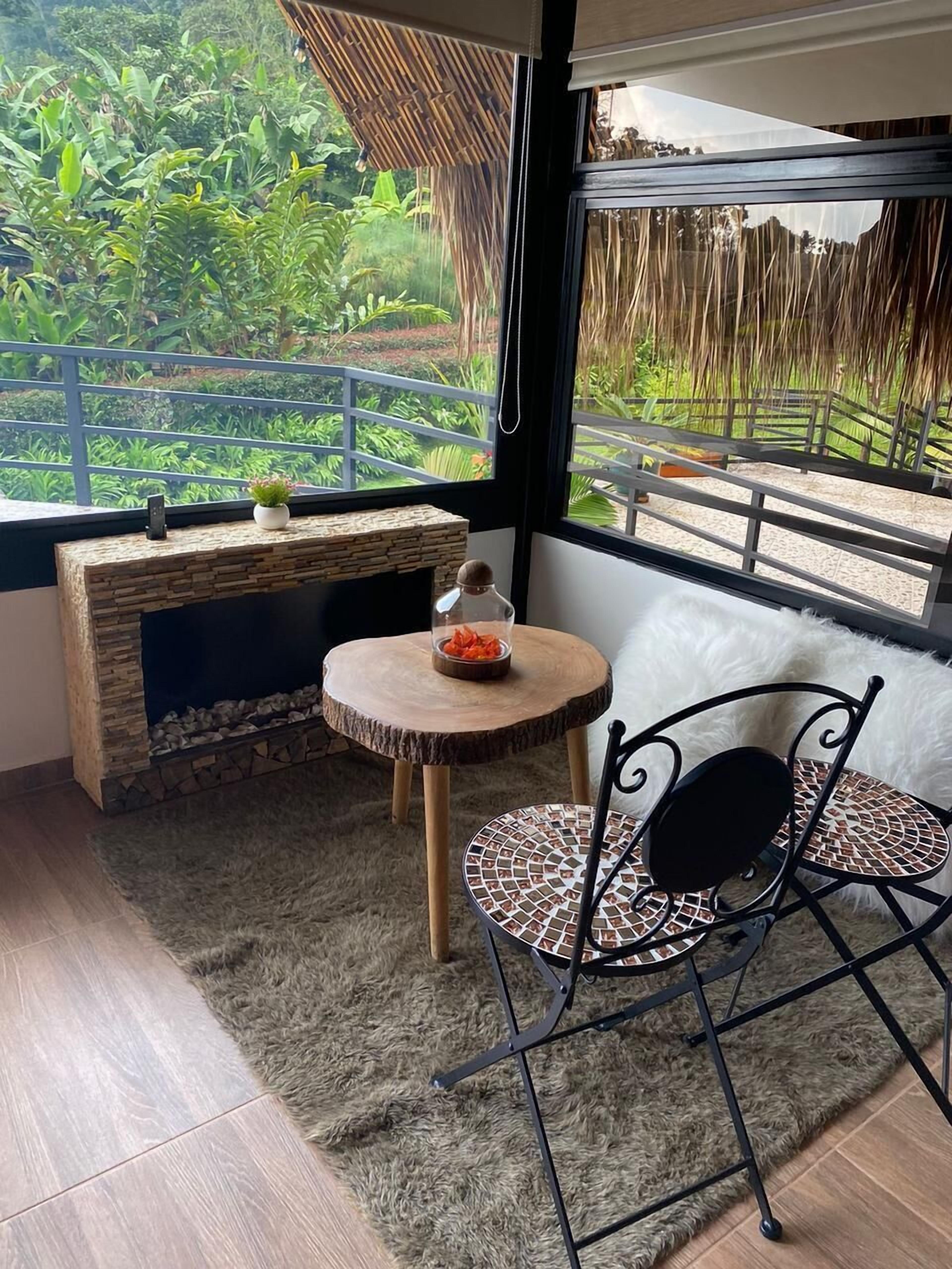 Una habitación acogedora con una chimenea de piedra, una mesa redonda de madera y una silla de metal negro.