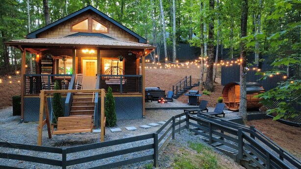 A cabin with a porch, outdoor seating, and a fire pit.
