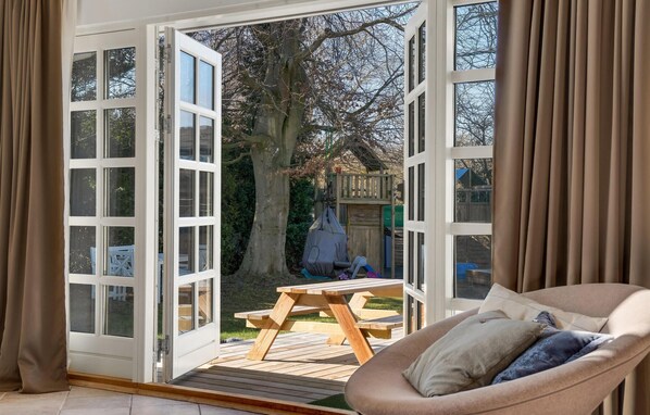 Relax in this serene space with a sliding glass door leading to an outdoor area featuring a deck with a picnic table and a hanging chair.