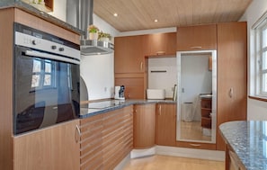 Enjoy cooking in this well-lit kitchen with a stainless steel range hood, oven, and countertop with sink and coffee maker.