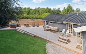 Relax in a serene outdoor space with a wooden deck, sofa, chairs, and dining table.