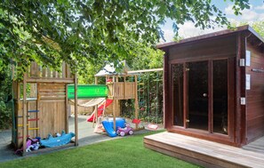 Children can play on the climbing structure, slide, and ride-on toys in this outdoor play area.