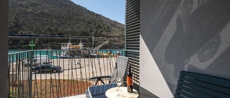 A balcony with a table, a bottle, and a glass.